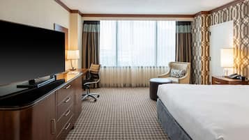 Une chambre d’hôtel équipée d’un grand téléviseur à écran plat, d’un lit, d’un bureau avec une chaise et d’un canapé.