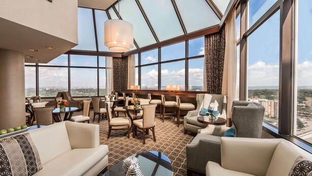 A spacious hotel lobby with a high ceiling, large windows, and a view of the cityscape. - Hilton Alexandria Mark Center (Alexandria)