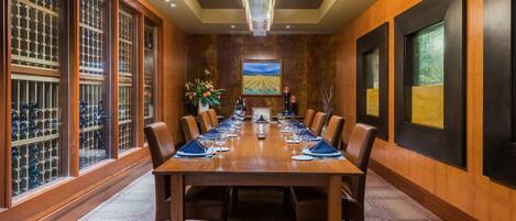A conference room with a long table, chairs, and a large window with a vineyard view.