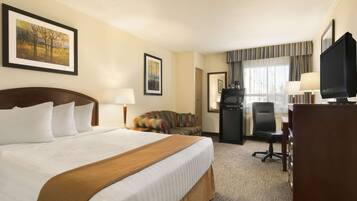 A hotel room with a large bed, a desk, a television, and a window with curtains.