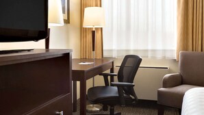 Une chambre d’hôtel équipée d’un lit, d’un bureau, d’une chaise, d’une télévision et d’une lampe.