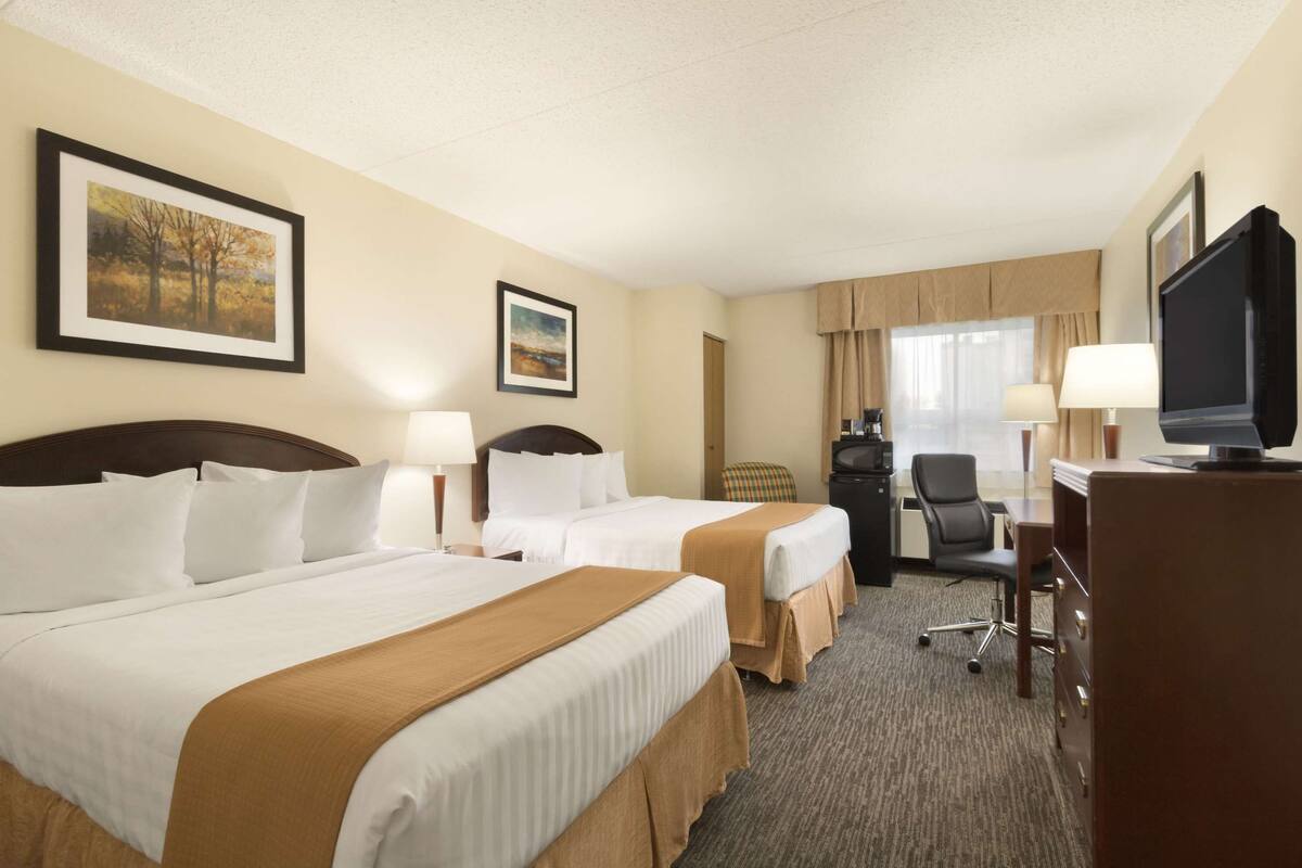 Een hotelkamer met twee bedden, een bureau, een televisie en een stoel.