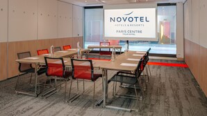 A modern conference room with a large screen displaying 'NOVOTEL HOTELS & RESORTS PARIS CENTRE TOUR EIFFEL'. - Novotel Paris Centre Tour Eiffel (Paris)