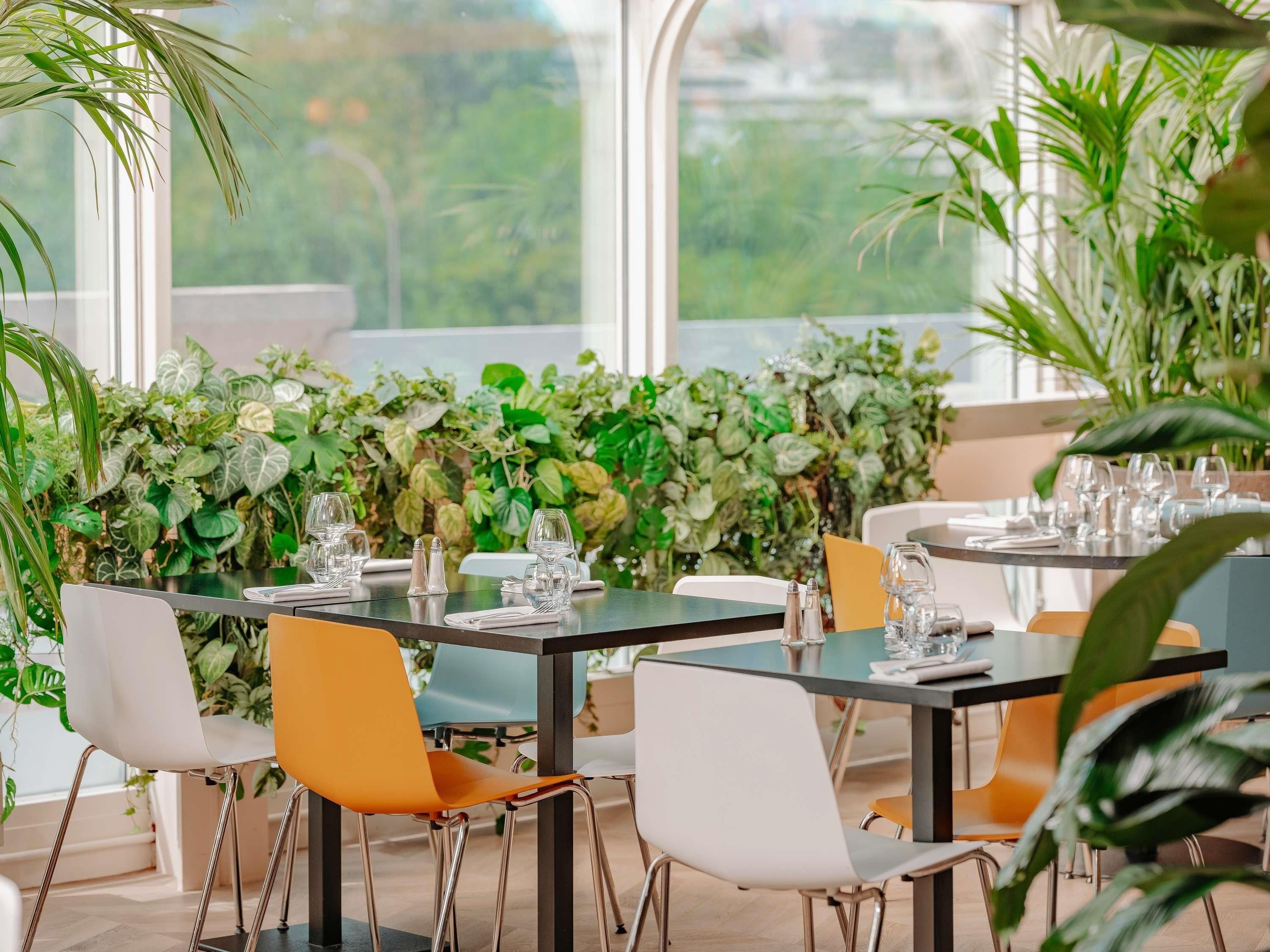 Un restaurante con mesas dispuestas para comer, rodeado de exuberante follaje verde.