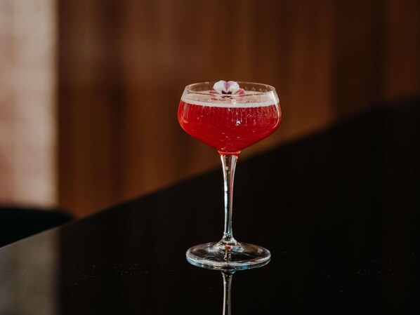 A cocktail in a stemmed glass with a decorative flower on the rim.