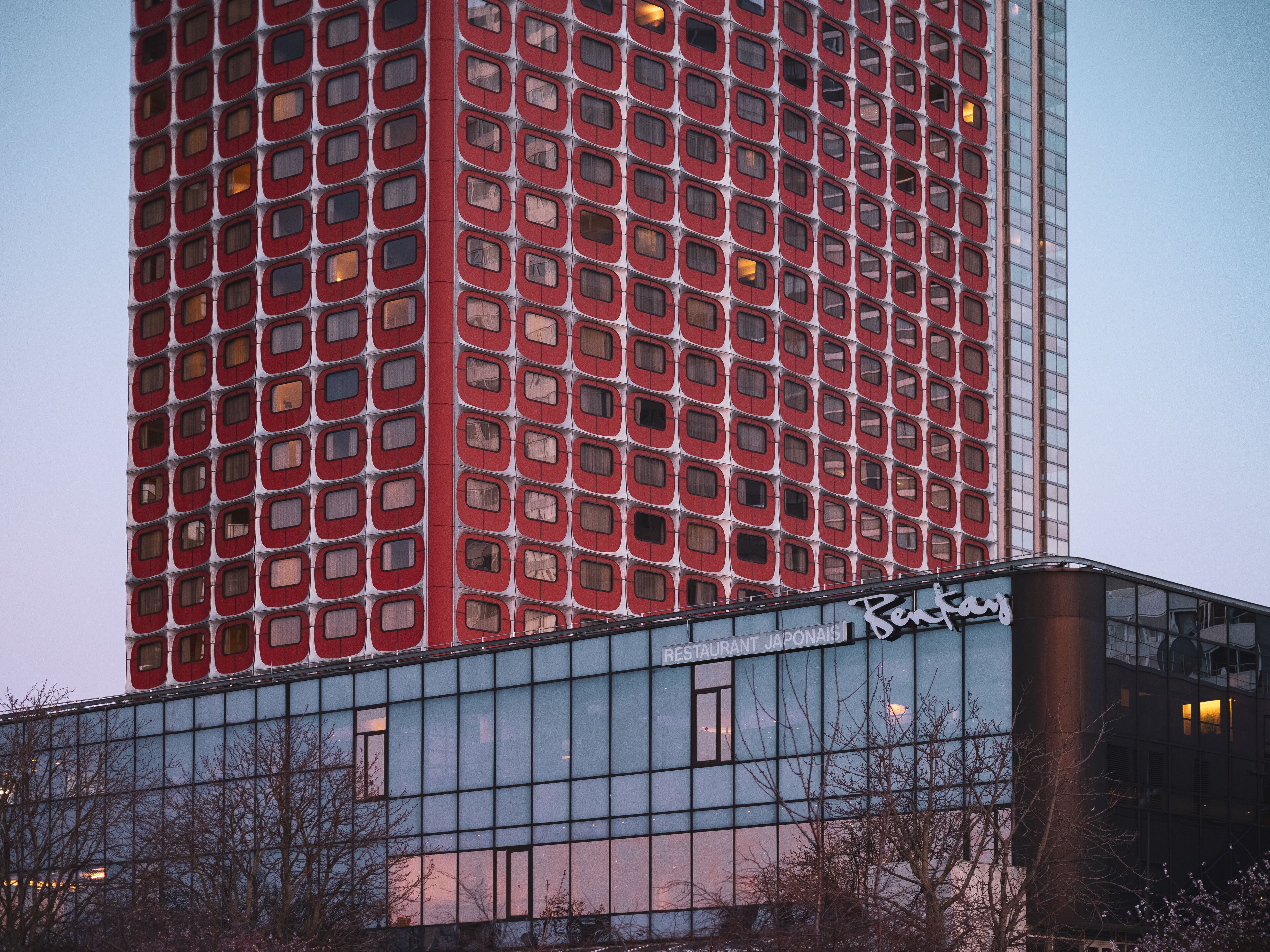 Un edificio alto con una fachada de ventanas y un letrero que dice "Restaurant Japonais" en la base.