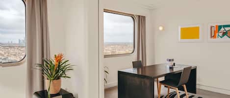 Una habitación de hotel moderna con vista a la ciudad, un comedor y arte abstracto en la pared.