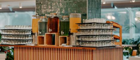 Zona de bar con varios dispensadores de bebidas y vasos apilados.