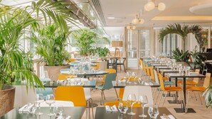A restaurant with indoor plants, tables set with glasses and cutlery, and a modern interior design. - Novotel Paris Centre Tour Eiffel (Paris)
