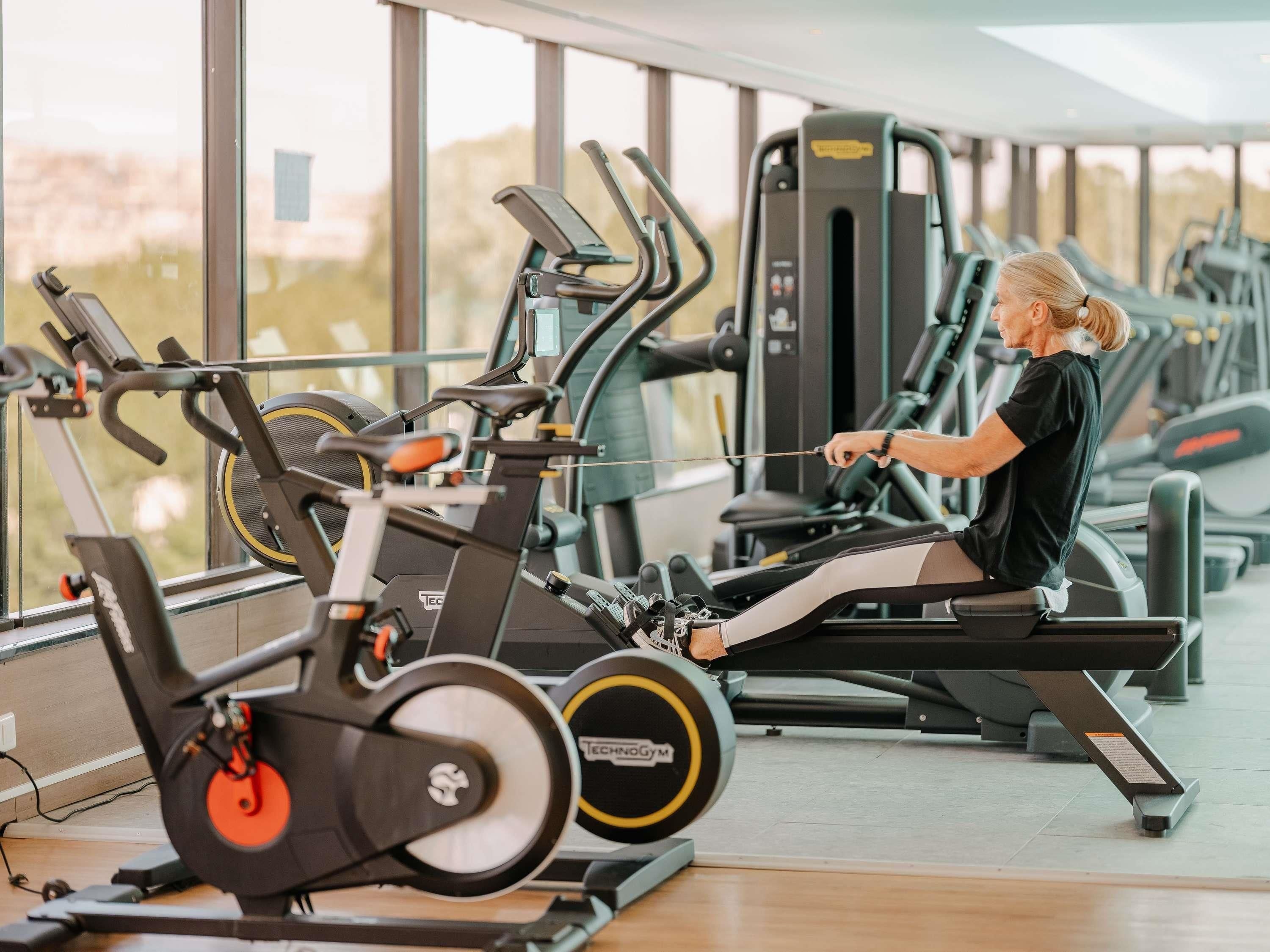 A gym with cardio machines and a person using a rowing machine.