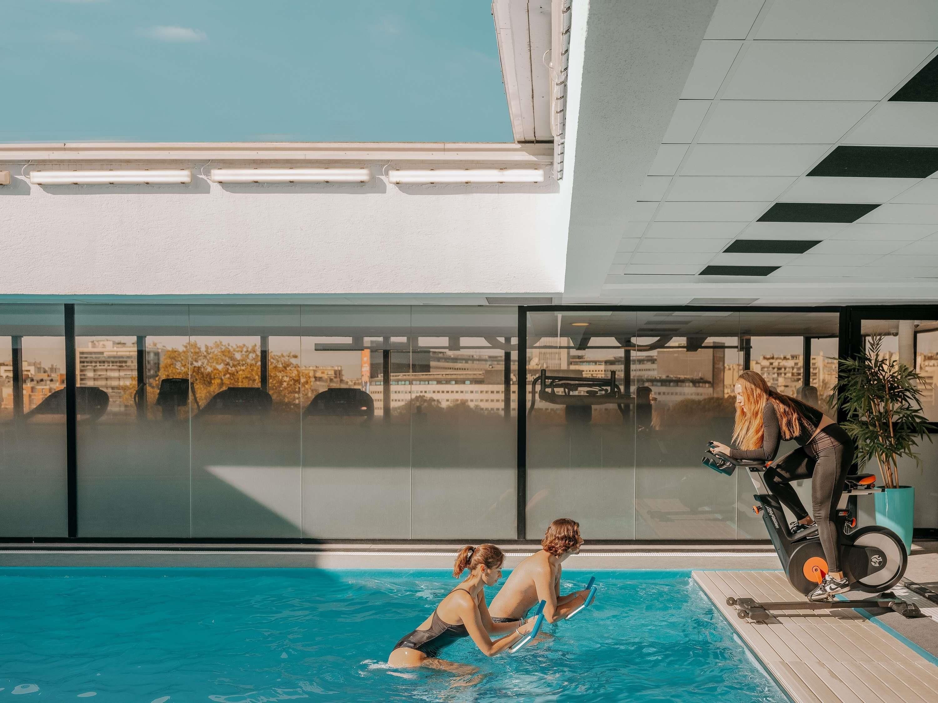 Une piscine offrant une vue sur le paysage urbain grâce à de grandes fenêtres.