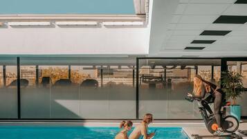 Une piscine offrant une vue sur le paysage urbain grâce à de grandes fenêtres.