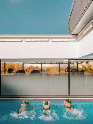 Una piscina con tres personas nadando.