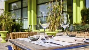 A table set outdoors with empty wine glasses, a menu, and a smartphone. - Ibis Styles Chalon sur Saone (Chalon-sur-Saone)