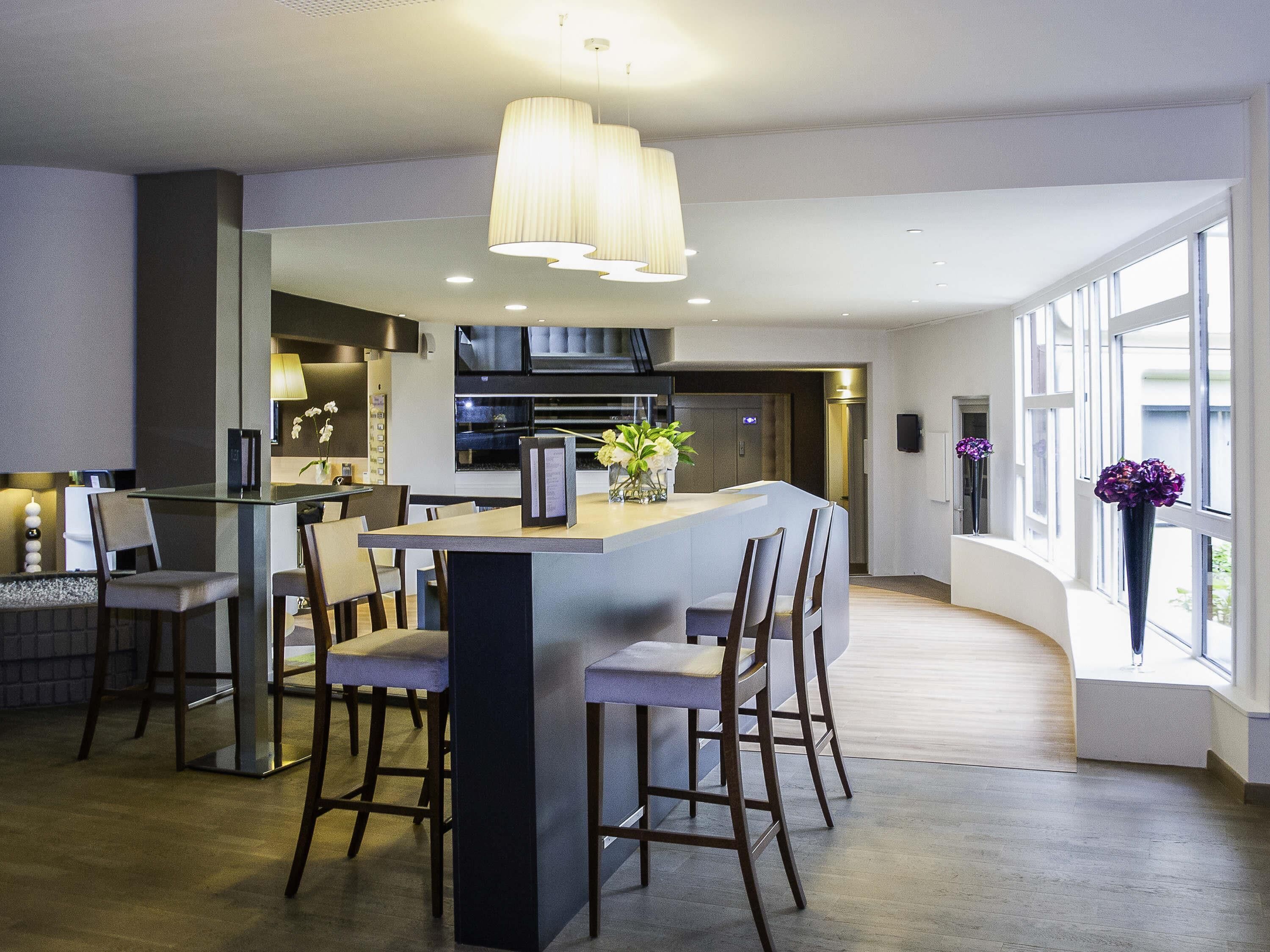 A modern kitchen with a central island, bar stools, and pendant lighting.