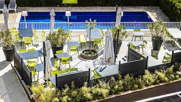 Een seizoensgebonden buitenzwembad en ligstoelen