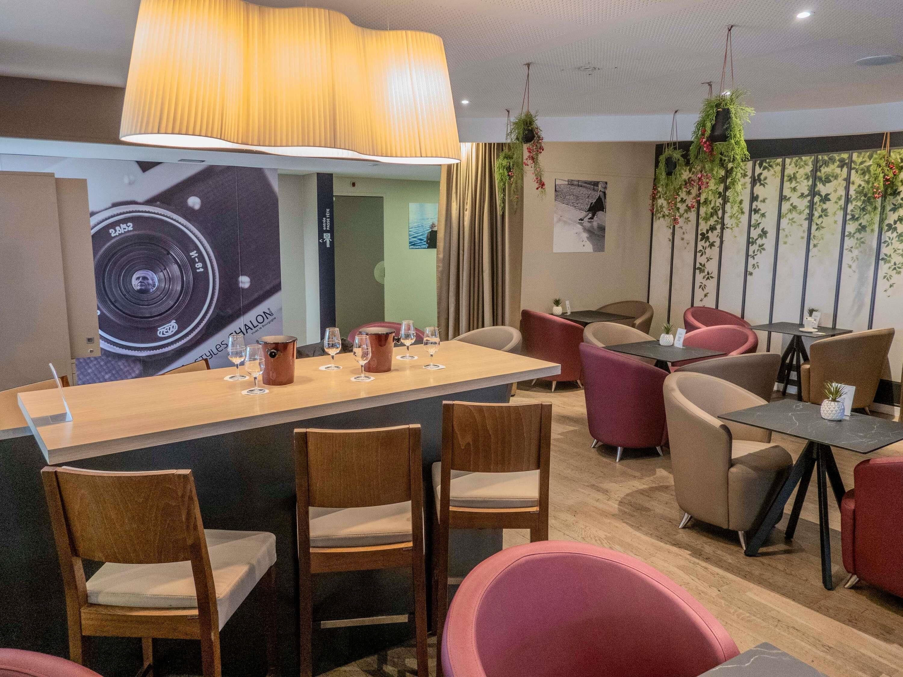 Un restaurante con barra, sillas de madera y plantas colgantes.