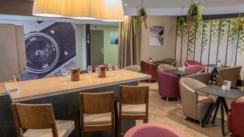 Un restaurante con barra, sillas de madera y plantas colgantes.