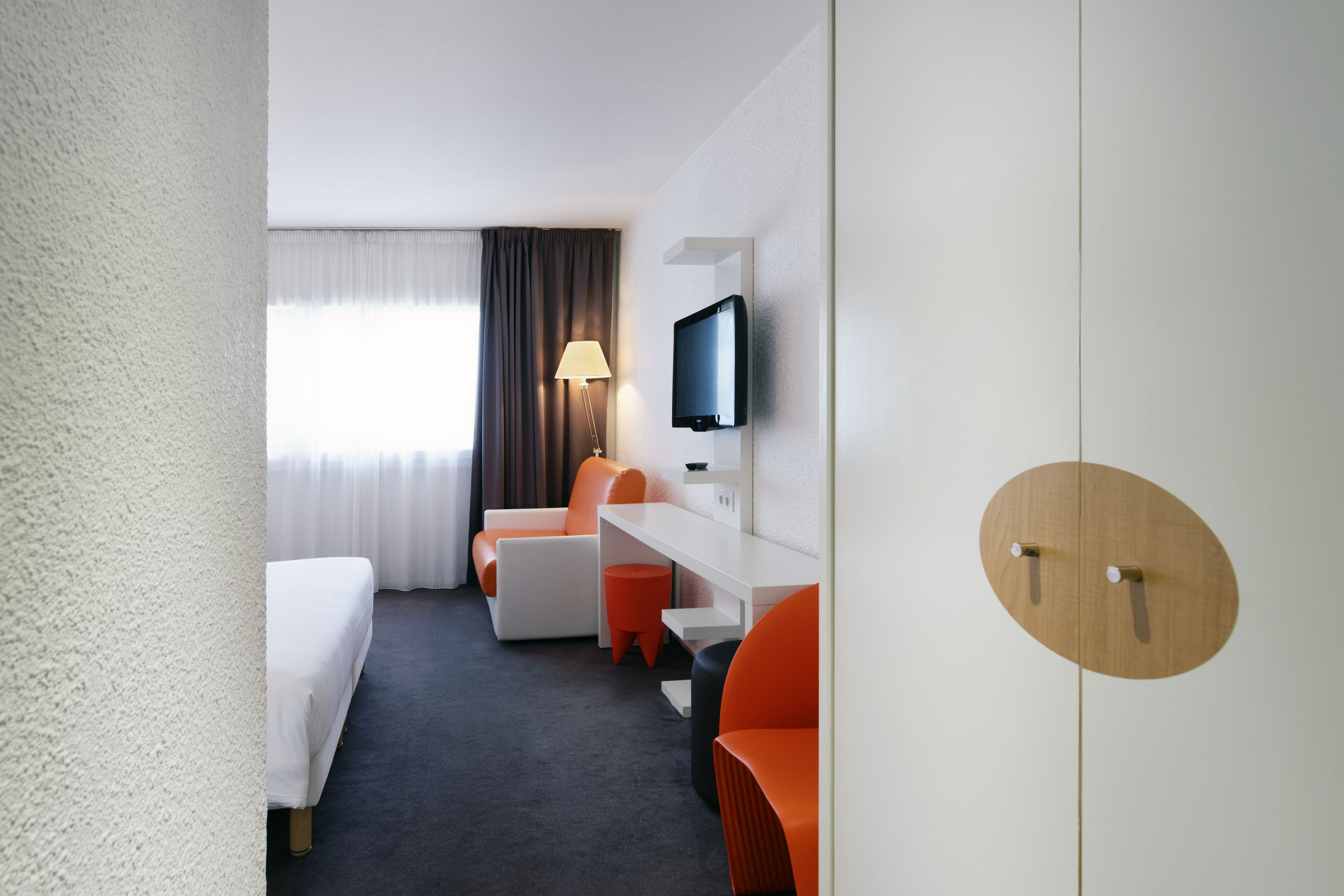 Een hotelkamer met een bed, een bureau, een stoel, een televisie en een kledingkast.
