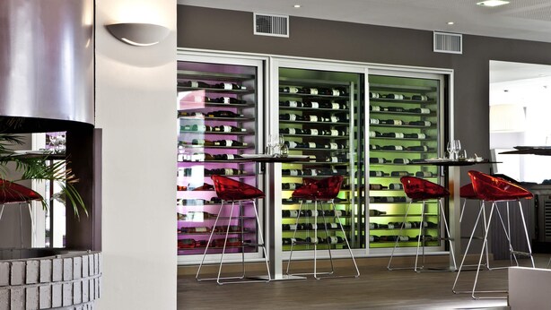 A modern interior with a wine cellar, red chairs, and a staircase. - Ibis Styles Chalon sur Saone (Chalon-sur-Saone)