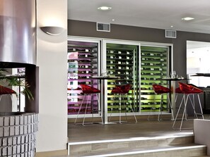 A modern interior with a wine cellar, red chairs, and a staircase.