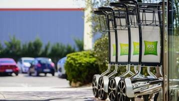 A row of wheelchairs with 'ibis Styles Hotels' signage, parked on a sidewalk.