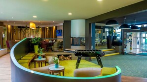 A modern lobby with a curved seating area, a fireplace, and a staircase leading to an upper level. - Ibis Styles Chalon sur Saone (Chalon-sur-Saone)