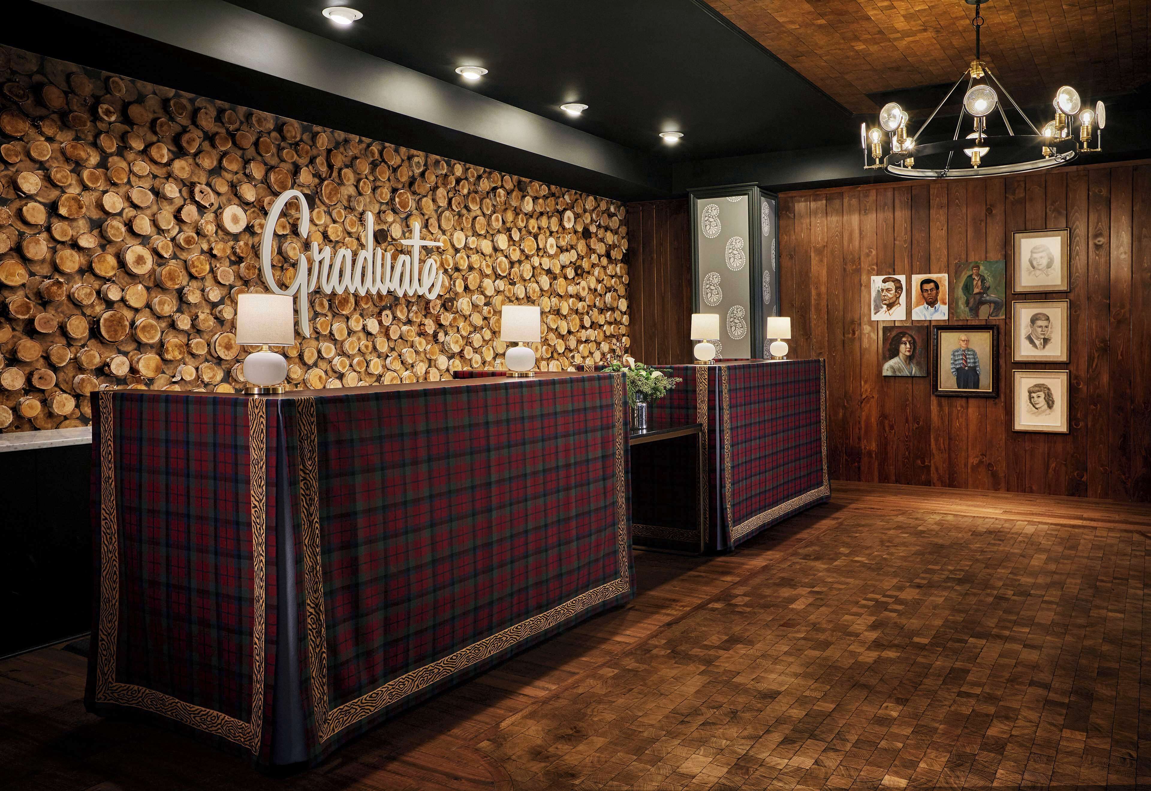 A reception area with a wooden log wall, a chandelier, and framed pictures on the wall.