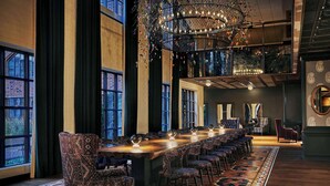 A long dining table with patterned chairs, a chandelier, and large windows. - Graduate by Hilton Minneapolis (Minneapolis)