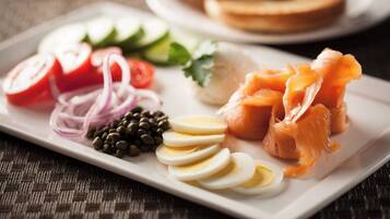 A plate with sliced salmon, eggs, tomatoes, onions, and capers.