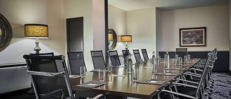 A conference room with a long table, chairs, and lamps.