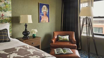Habitación de hotel con cama, un sillón de cuero marrón, lámpara de lectura, un cuadro en la pared y una ventana con cortinas.