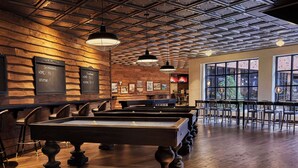 A billiards room with wooden walls and ceiling, a pool table, and multiple chairs. - Graduate by Hilton Minneapolis (Minneapolis)