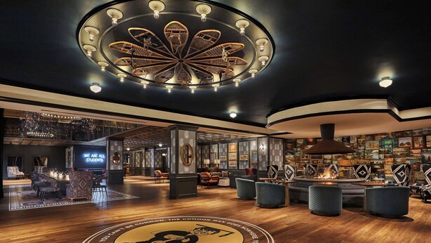 A spacious lobby with a central circular emblem, a high ceiling with a decorative light fixture, and a bar area with seating. - Graduate by Hilton Minneapolis (Minneapolis)