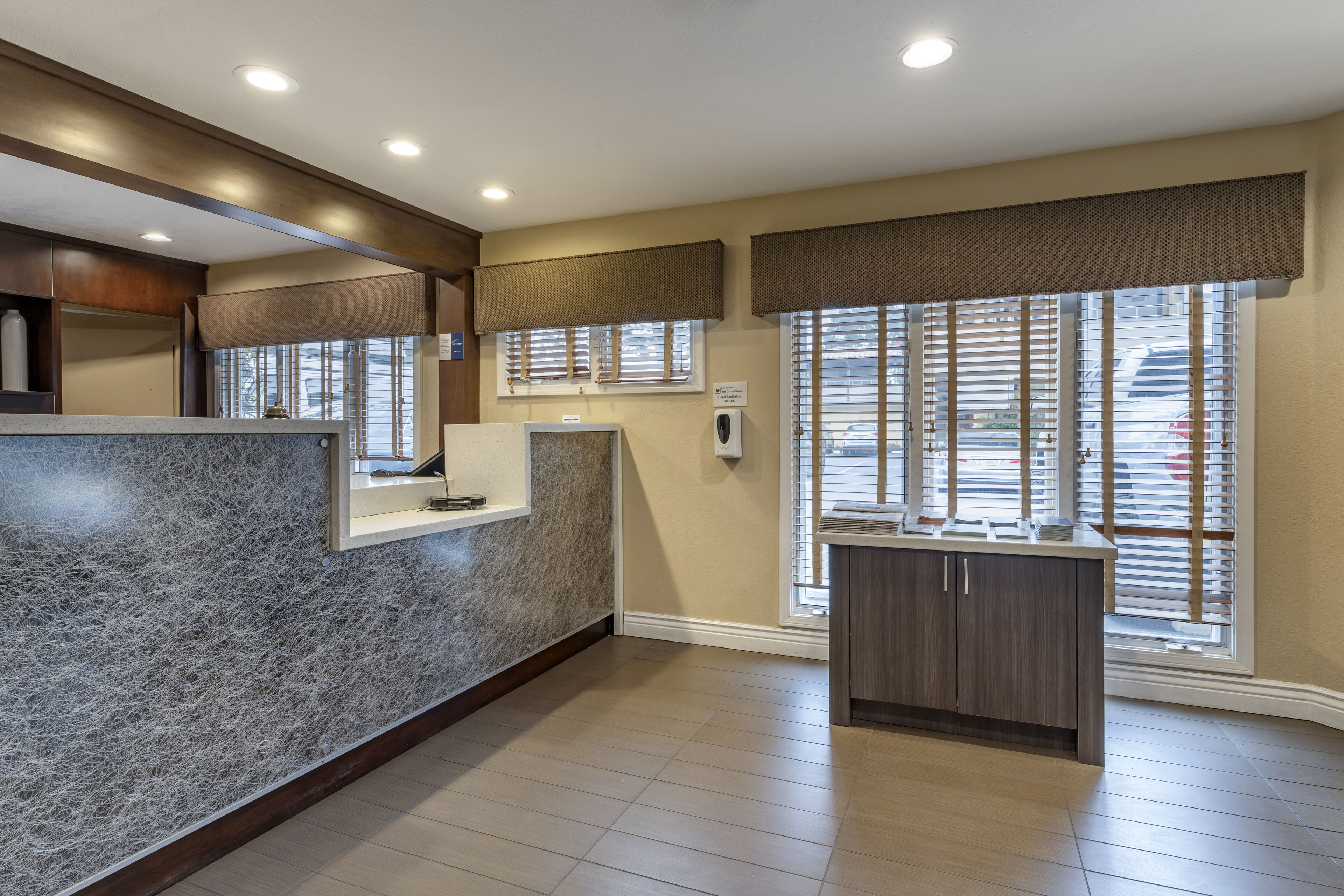 A modern kitchen with a granite countertop, wooden cabinets, and a window with blinds.