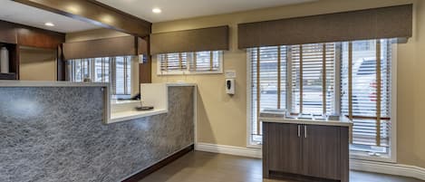 A modern kitchen with a granite countertop, wooden cabinets, and a window with blinds.