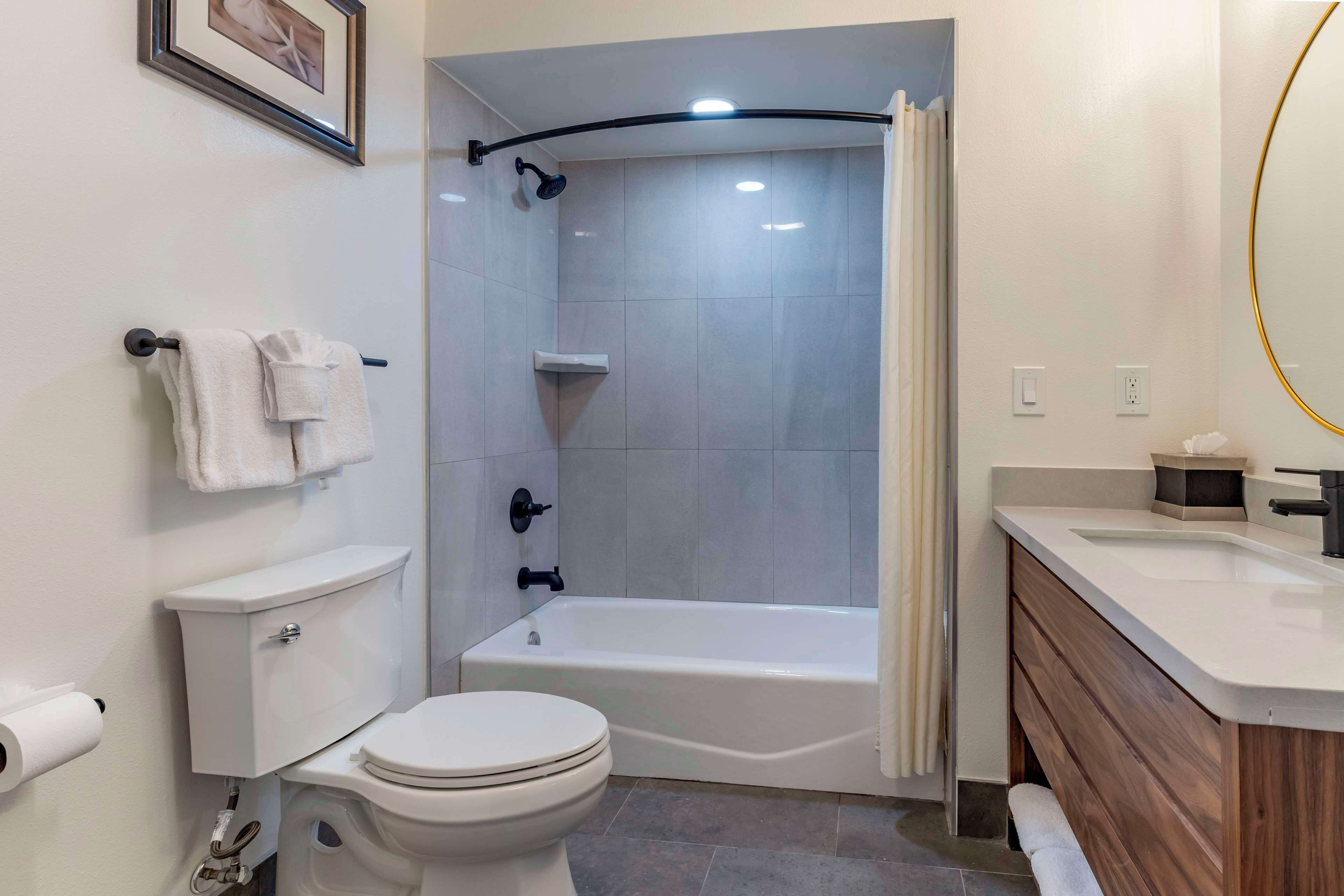A modern bathroom with a toilet, bathtub, and vanity.
