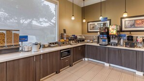 Een moderne keuken met een bedieningsstation, inclusief een koffieapparaat, broodrooster en een vitrine met eten.