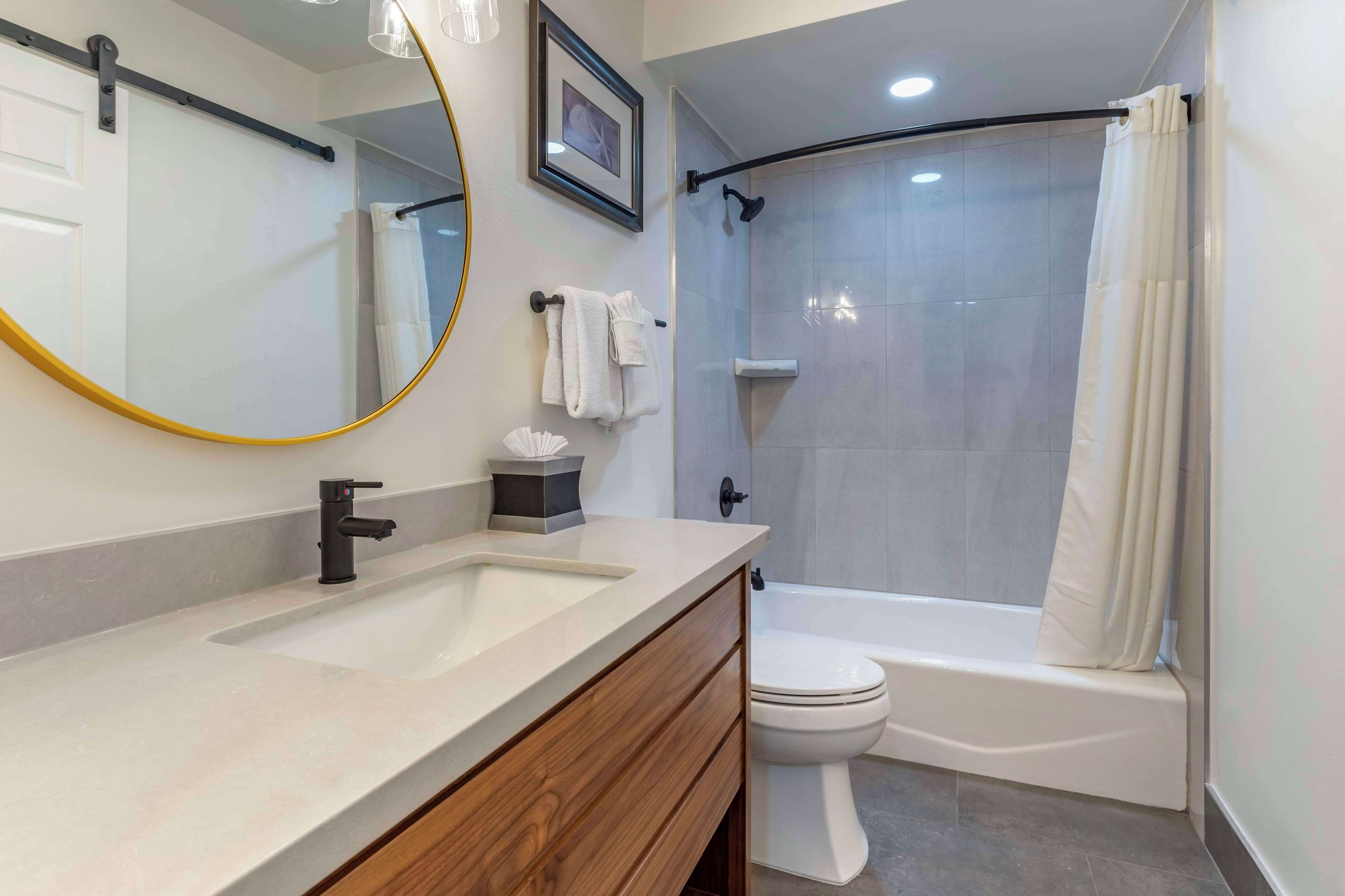 A modern bathroom with a sink, mirror, toilet, and shower.