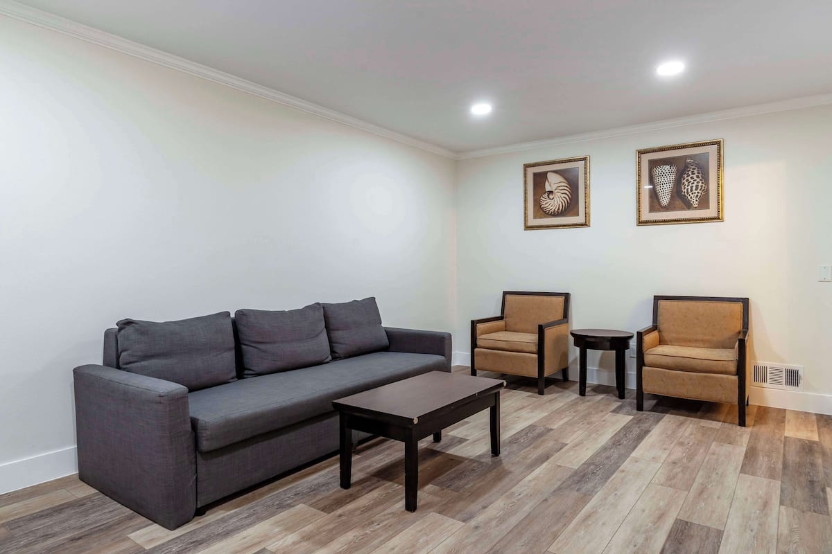 Ein Wohnzimmer mit grauem Sofa, zwei Sesseln, einem Couchtisch und Holzboden.