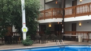 An indoor swimming pool with a stone deck and metal handrails. - Shawano Four Seasons Hotel (Shawano)
