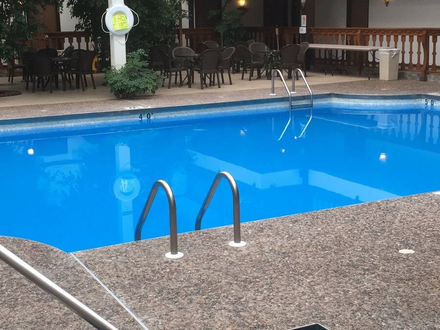 Une piscine intérieure dotée d’une plage en pierre et de rampes métalliques.