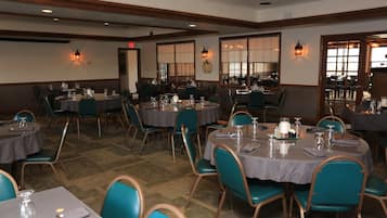 A dining area with round tables, teal chairs, and a mix of table settings.