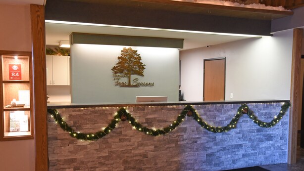 A reception area with a stone wall, a Christmas tree decoration, and a sign that reads "Four Seasons." - Shawano Four Seasons Hotel (Shawano)