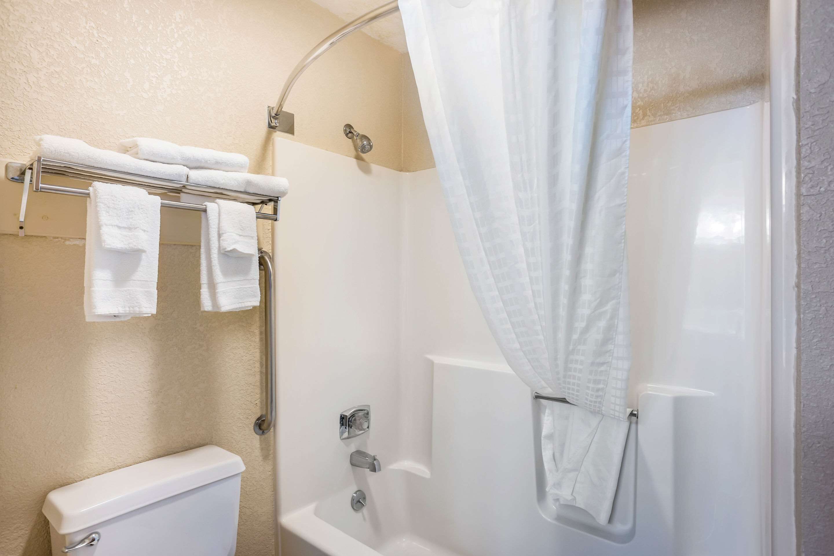 Ein Badezimmer mit Toilette, einer Duschkabine und einem Handtuchhalter mit Handtüchern.
