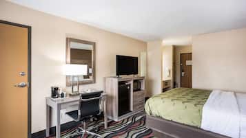 Ein Hotelzimmer mit Bett, Schreibtisch, Stuhl, Fernseher und Spiegel.