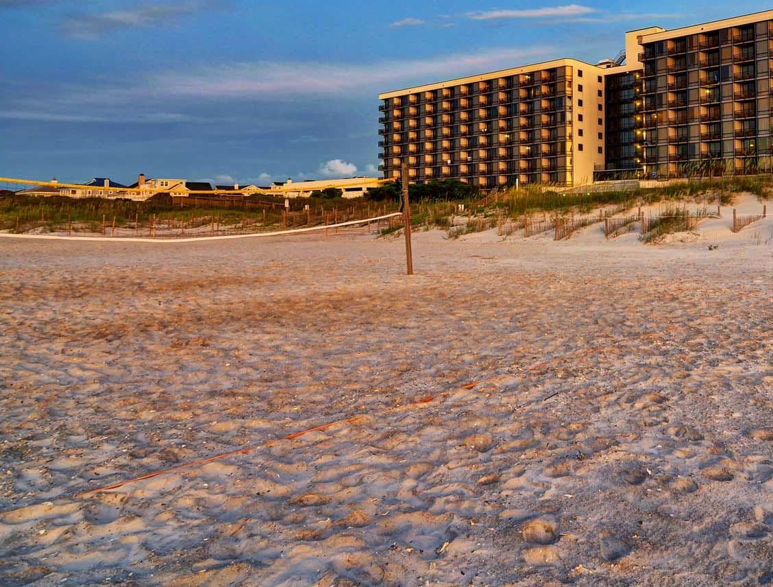 A beachfront hotel with a modern design, featuring multiple floors and a prominent entrance.