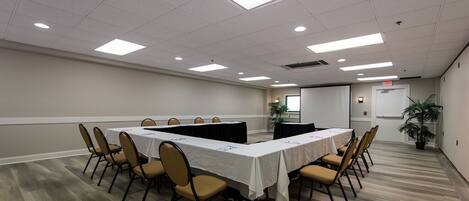 A conference room with a long table, chairs, and ceiling lights.