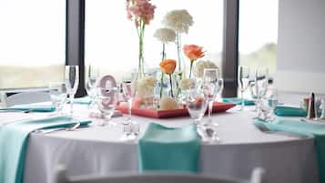 Mesa lista para comer, con cristalería transparente, un centro de flores y mantel color turquesa.