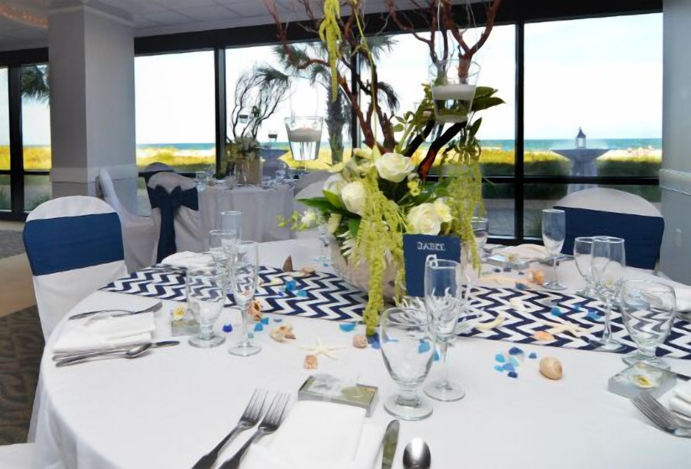 A table set for a meal with a view of the beach, name card holder, and decorative elements.